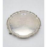 An Elizabeth II silver waiter, with chippendale style pie crust rim, supported on three feet, with
