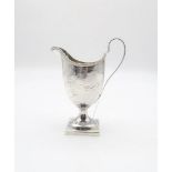 A George III silver cream jug, of helmet form, with cast beaded rim, with engraved scrolling foliate