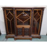 An early 20th century oak glazed bookcase with central glazed door above cabinet doors flanked by