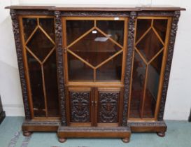 An early 20th century oak glazed bookcase with central glazed door above cabinet doors flanked by