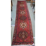 A red ground Heriz runner with geometric medallions and multicoloured border, 381cm long x 88cm wide