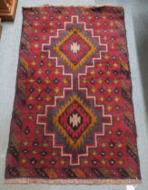 A red ground Balouch rug with dual central medallion and multicoloured border, 134cm long x 86cm