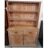 A 20th century pine dresser with two open shelves above two drawers above a pair of cabinet doors