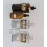 A collection of five brown and clear glass chemists bottles, one for Aqua Chloroe, another for Calum