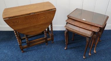 A 20th century mahogany nest of three tables and an oak drop leaf table with carved bobbin