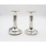 A pair of Edwardian silver candlesticks, the column decoration with floral ribbon swags, on a
