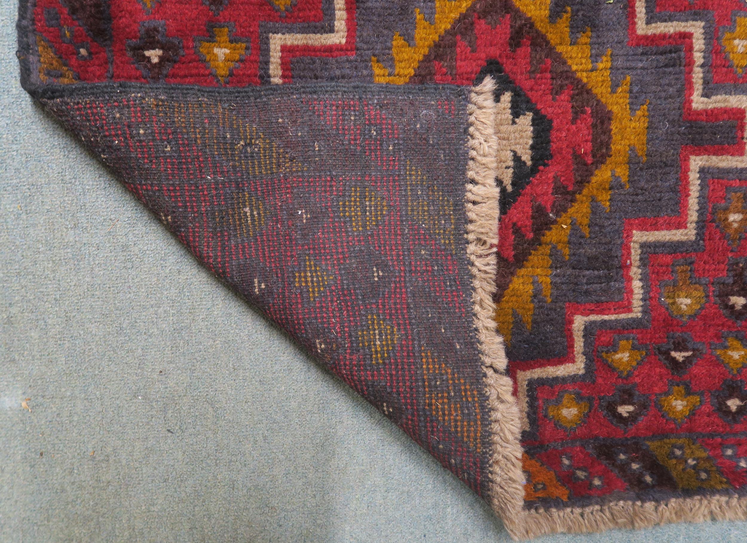 A red ground Balouch rug with dual central medallion and multicoloured border, 134cm long x 86cm - Image 2 of 2