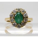 A bright yellow metal ring, stamped 750, set with emerald and diamonds set with estimated approx 0.