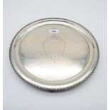 A George V circular silver salver, with applied beaded rim, on three bracket feet, with