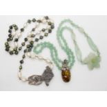 A green hardstone bead necklace with a carved flower together with an amber pendant and a