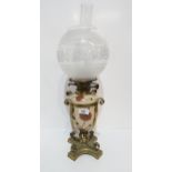 A ceramic and brass cased oil lamp, the body decorated with flowers, with a frosted glass shade,