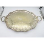 A large silver plated twin handled serving tray, the scalloped body engraved with scrolling