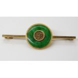 A CHINESE GREEN HARDSTONE RONDEL BROOCH with Chinese symbols mounted to the middle, the bar brooch