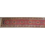 A RED GROUND TURKISK DOSEMEALTI RUNNER with multicoloured geometric medallions, dark blue