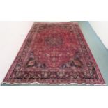 A RED GROUND MESHED RUG with dark blue central medallion and matching spandrels