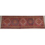 A RED GROUND KARADJA RUNNER with five geometric medallions and beige borders, 317cm long x 94cm wide