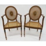 A PAIR OF EARLY 20TH CENTURY SHERATON REVIVAL OPEN ARMCHAIRS with cane seat and oval back centred in