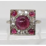 A RUBY AND OLD CUT DIAMOND RING the white metal mount is set with a central ruby cabochon with