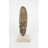 AN IVORY COAST BONE CARVED MASK the elongated face with narrow eyes, scarred face and wide mouth, on