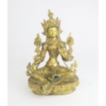 A GILT BRONZE MODEL OF THE TIBETAN GODDESS TARA seated in typical pose on a lotus throne