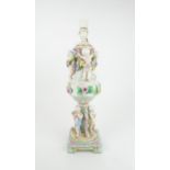 A CONTINENTAL PORCELAIN URN SHAPED LAMP decorated with putti with swags of flowers and applied