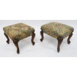 A PAIR OF VICTORIAN UPHOLSTERED FOOTSTOOLS with carved walnut cabriole supports, 35cm high x 43cm