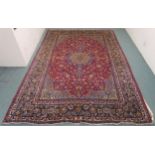 A RED GROUND MESHED RUG with floral central medallion, matching spandrels