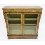 A VICTORIAN BURR WALNUT GLAZED BOOKCASE with two glazed doors concealing two shelves, brass ormolu