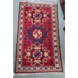 A red ground geometric pattern rug with three medallions and cream borders, 182cm high x 104cm