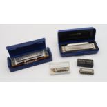 A lot comprising two Hohner blues harps in D, a Hohner Little Lady harmonica and a Hero harmonica.