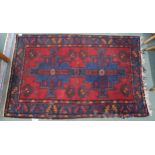 A red ground Belouch rug with two blue medallions and multicoloured borders, 157cm long x 100cm wide