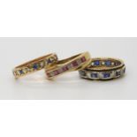 Three gem set eternity rings, a ruby and diamond, size N, a blue and clear gem, size N1/2,