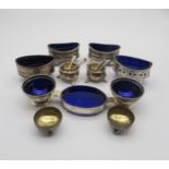A collection of silver salts, many with blue glass liners, a pair by Elkington & Co, London 1913,