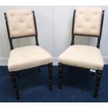 A pair of Victorian ebonised parlour chairs with cream upholstered back and seats on turned supports