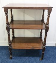 A Victorian mahogany three tier what-not with turned uprights on brass casters, 111cm high x 76cm