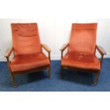 A pair of mid 20th century teak framed Guy Rogers "Manhattan" reclining armchairs upholstered in red