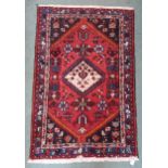 A red ground eastern rug with dark blue spandrels and multiple borders, 149cm long x 101cm wide