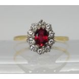 A bright yellow metal ruby and diamond cluster ring, dimensions of the ruby approx 6mm x 4mm, set