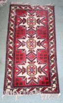 A red ground Persian rug with three geometric medallions and cream borders, 191cm long x 104cm