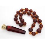 A string of mixed amber coloured beads weight 104gms, together with a ruby glass scent bottle with