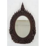 A 20th century eastern oval wall mirror extensively carved throughout, 89cm high x 51cm wide