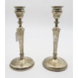 A pair of Edwardian silver candlesticks, of tapering form, the nozzles on capstan supports, on