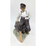 A large Royal Copenhagen figure of a seated boy on a rock holding a fishing rod, designed by