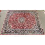A RED GROUND KESHAN RUG with blue central medallion, matching spandrels and dark blue border,