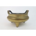 A CHINESE BRONZE TRIPOD CENSER with raised loop handles and dragon seal mark, 20cm high and 28cm