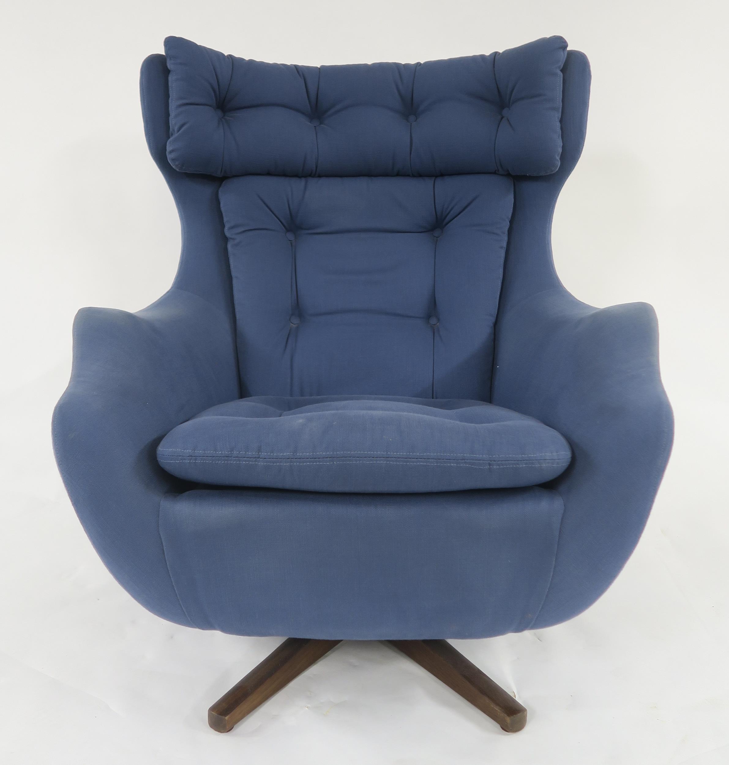 A MID 20TH CENTURY PARKER KNOLL "STATESMAN" SWIVEL ARMCHAIR with blue buttoned upholstery on stained