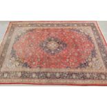 A LARGE RED GROUND KESHAN RUG with all over floral foliate design, dark blue central medallion,