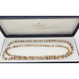 A STRING OF SCOTTISH RIVER PEARLS retailed by Cairncross of Perth, in shades of brown and cream,