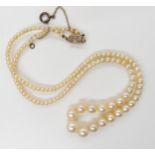A STRING OF GOOD QUALITY PEARLS with a yellow and white metal diamond clasp, the largest pearl is