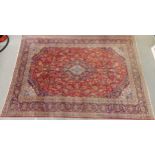 A RED GROUND TABRIZ RUG with all over floral foliate design, dark blue central medallion, matching